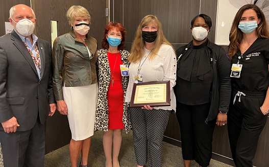 Robin Ford stands among leadership and peers holding her Nurse of the Year plaque. Everyone is wearing masks.