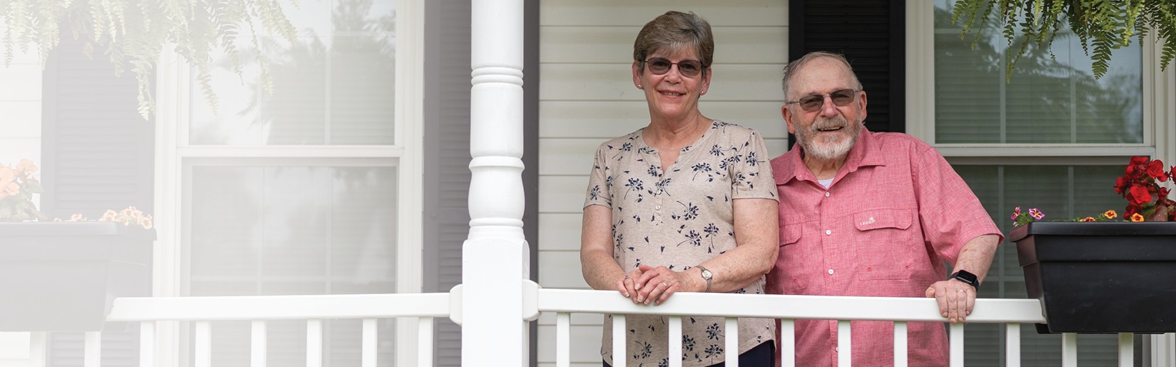 Cathy standing on the porch with her husband.